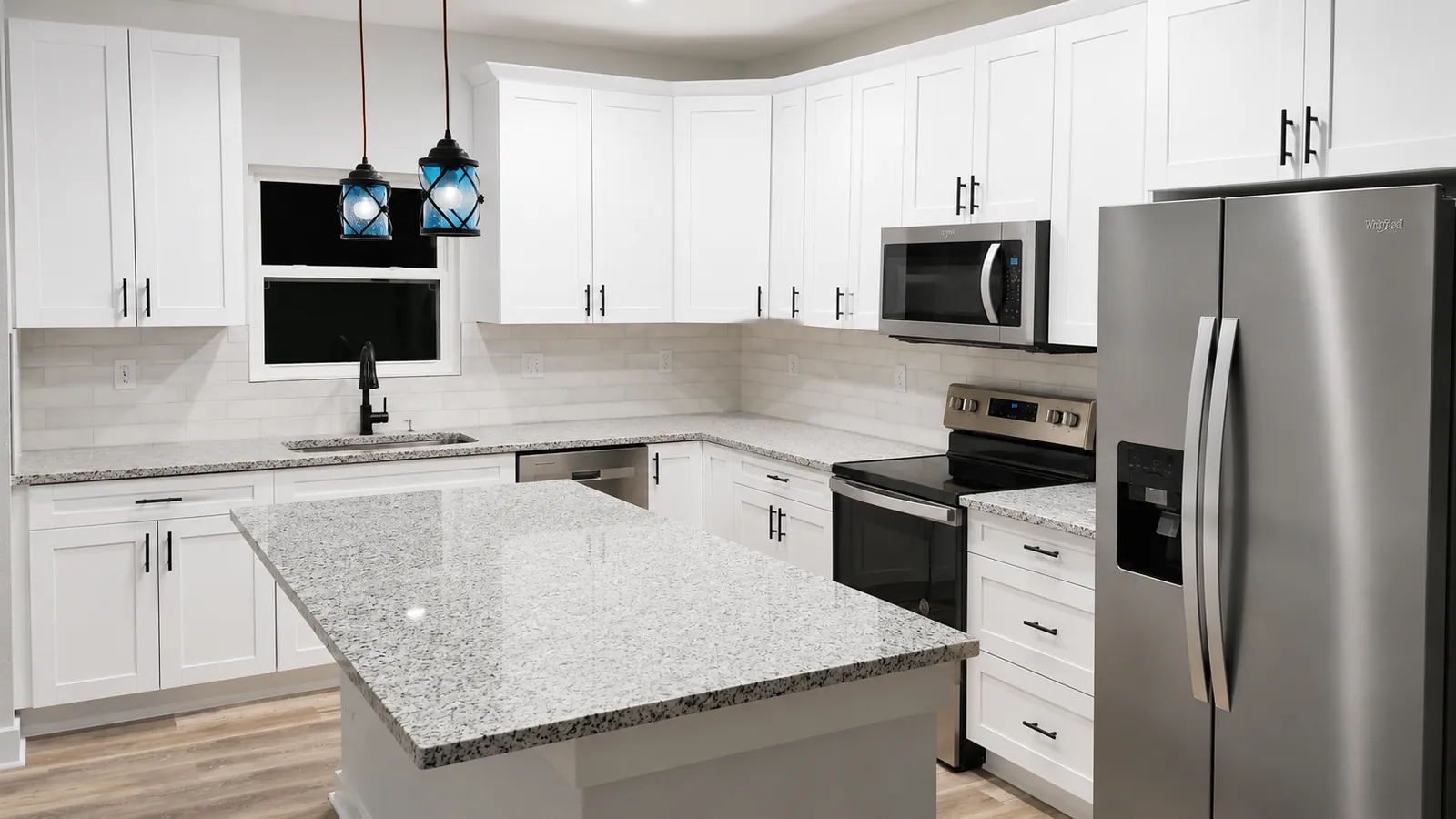 White shaker kitchen with granite island and stainless appliances